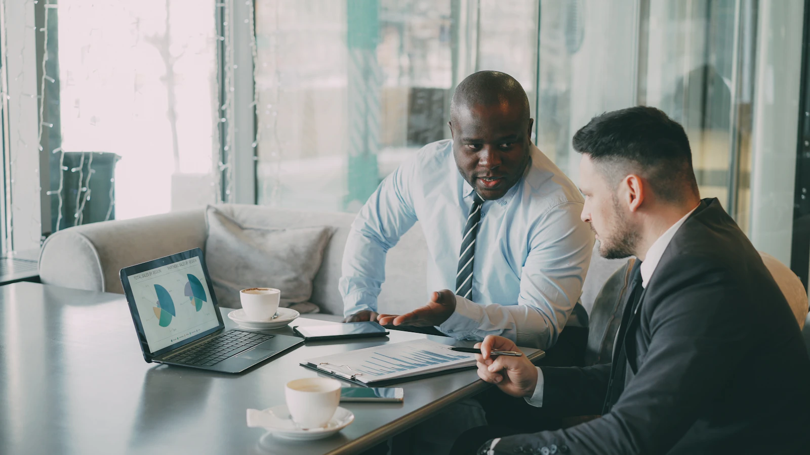 Two businessmen discussing charts on a laptop